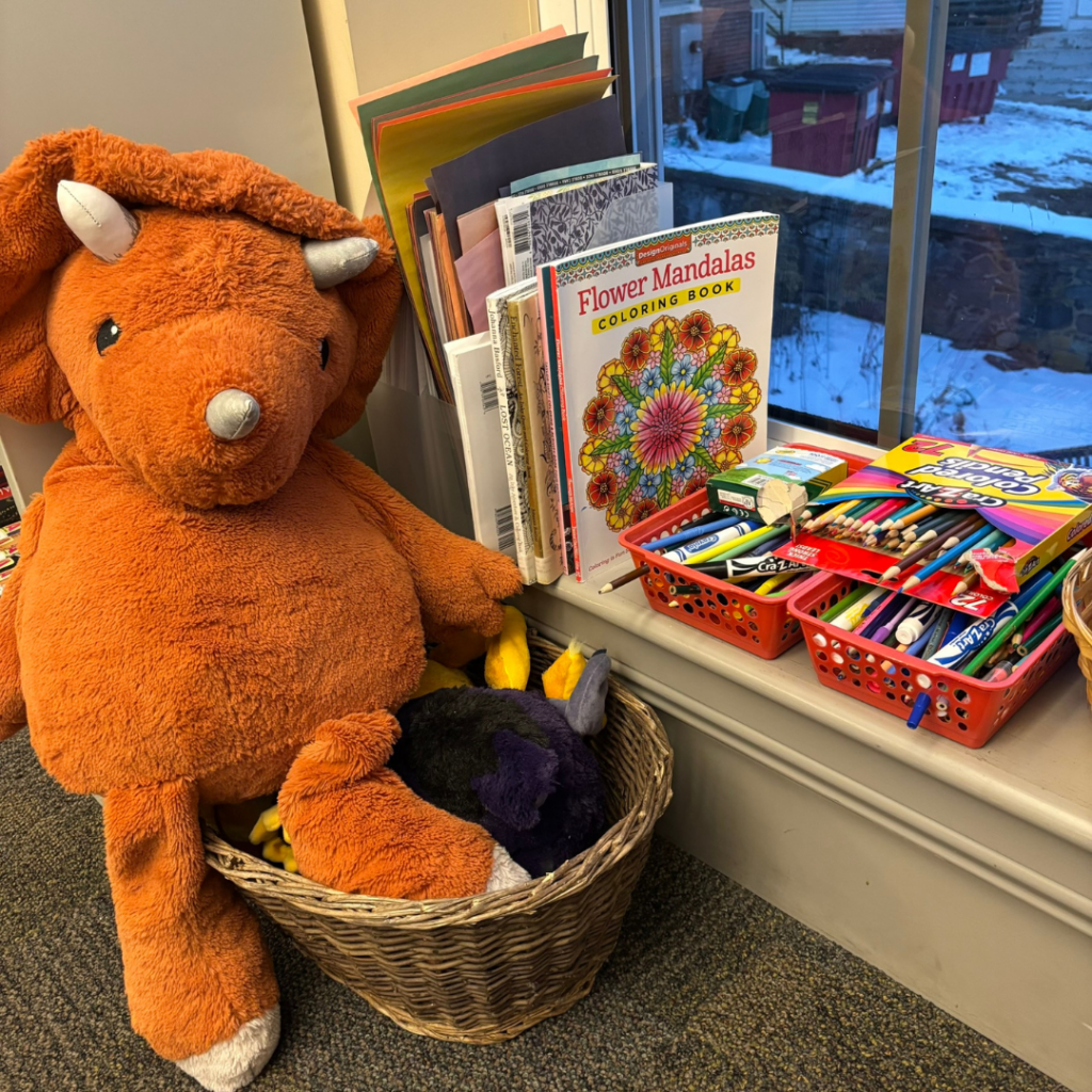 Photo of craft supplies next to a stuffed dinosaur.